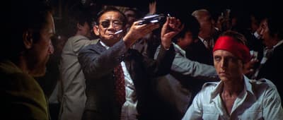 We need to translate the title: "Was a Live Gun Used in the Film “Deer Hunter”?" into German. Should be something like: "Wurde eine echte Waffe im Film „Der Jäger“ verwendet?" But the film title "Deer Hunter" is known as "Der Jäger" in German? Actually the German title is "Der Jäger" or "Der Hirschjäger"? I think the German release title is "Der Jäger". However, we might keep the original title in quotes. The translation: "Wurde eine echte Waffe im Film „Deer Hunter“ verwendet?" Or "Wurde eine echte Waffe im Film „Deer Hunter“ benutzt?" Better: "Wurde