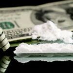 Cocaine snorted on a mirror through rolled 100 dollar bank note, close up view