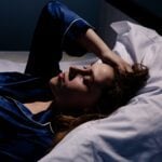 Upset woman lying in bed in sleepless.